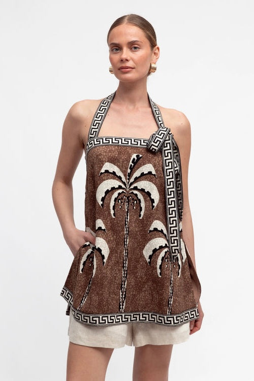 Woman wearing a brown halter top with palm tree design on a white background
