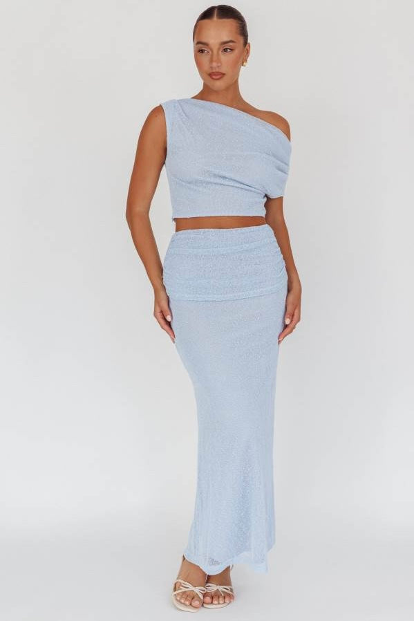 Woman wearing a light blue one-shoulder top and skirt set on a white background