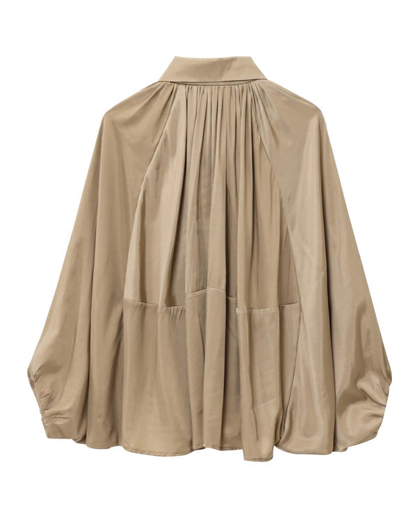 A beige long-sleeve blouse with a high gathered neckline, pleated front details, and large patch pockets, shown against a plain white background.