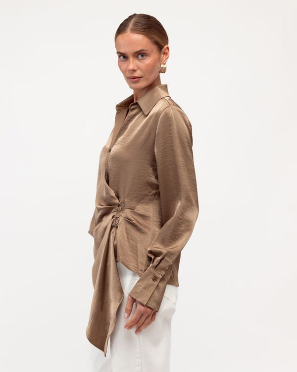 Woman wearing a brown shirt with a tie detail on a white background