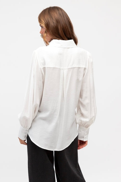 Woman wearing a white blouse with a subtle pattern on a white background