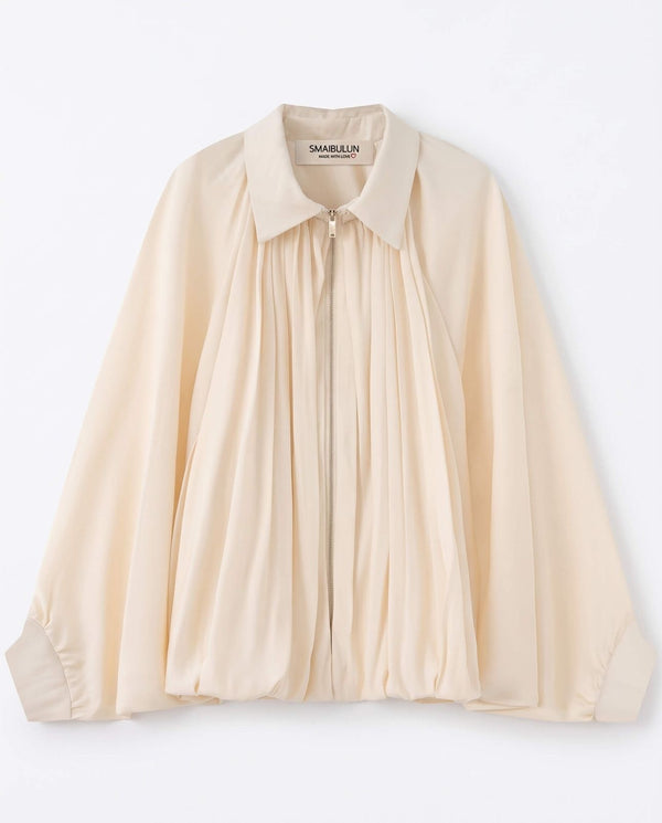 A cream-colored long-sleeve blouse by Samuella, featuring a pleated front design, a pointed collar, and a button-up front, laid flat against a white background.
