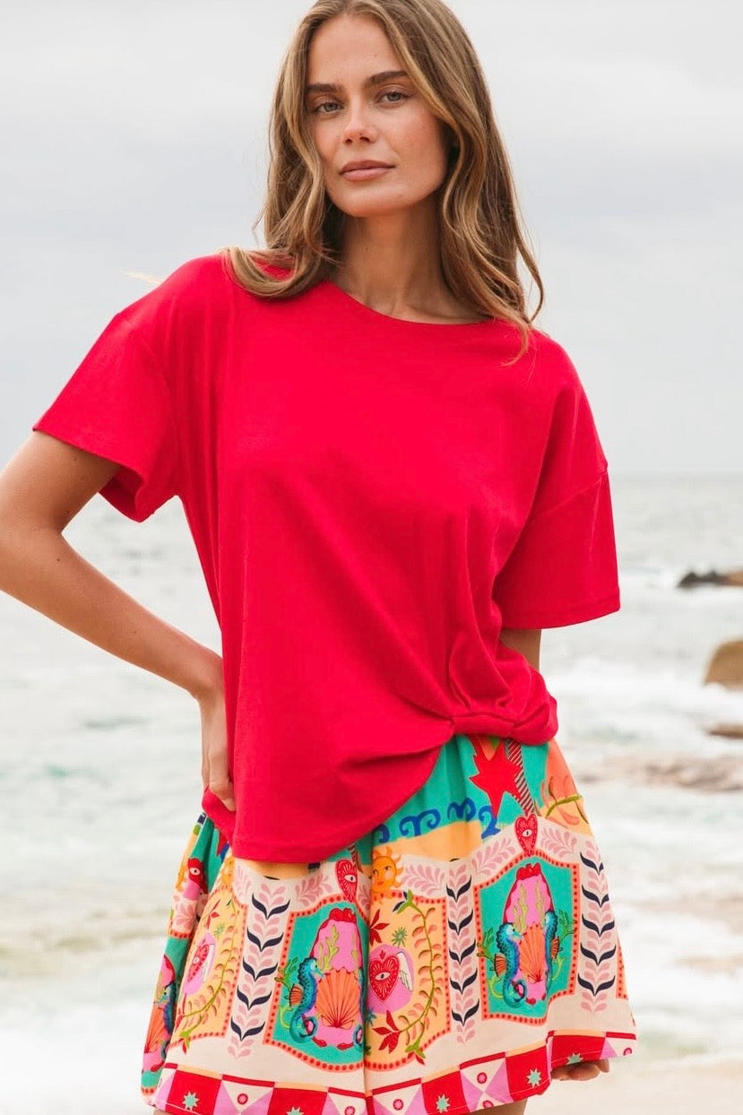 Woman wearing a red top and colorful skirt on a beach