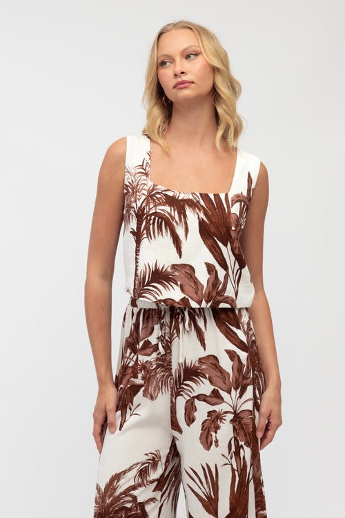 Woman wearing a sleeveless top with brown leaf pattern on a white background