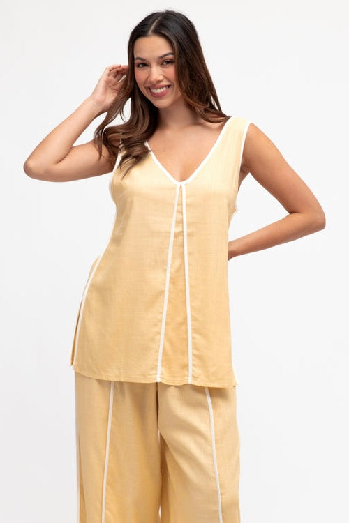 Woman wearing a yellow sleeveless top and pants set on a white background