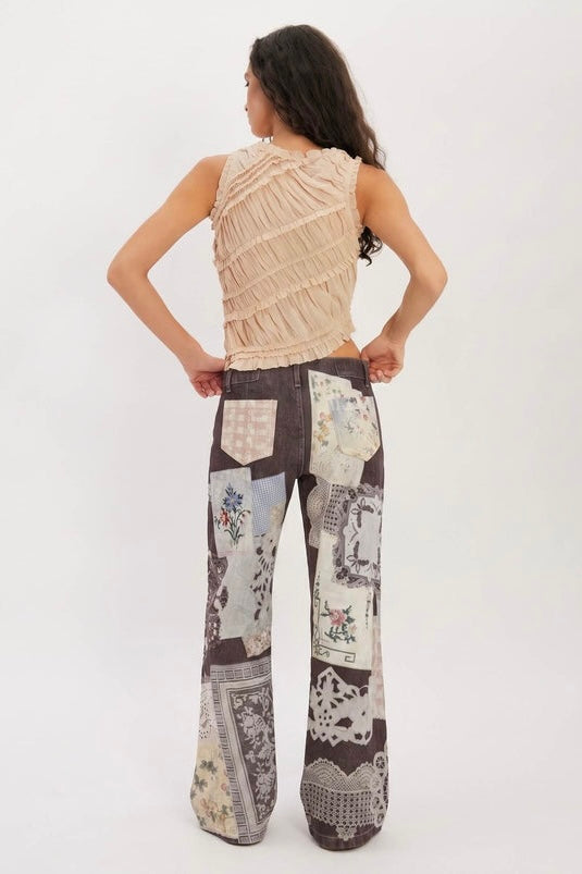 Back view of the Parise Patch Jean showing the patchwork print detail and back pockets, styled with a blush ruffle sleeveless top against a white studio background.