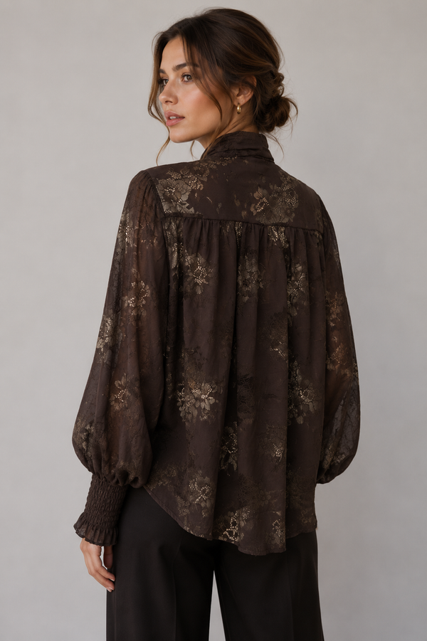 Woman wearing a dark floral blouse against a plain background