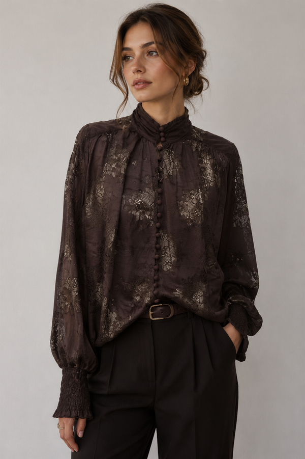 Woman wearing a dark brown floral blouse with a plain background