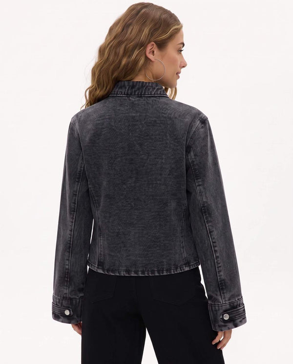 A woman shown from the back wearing a cropped dark gray washed denim jacket and black pants, photographed against a plain light background.