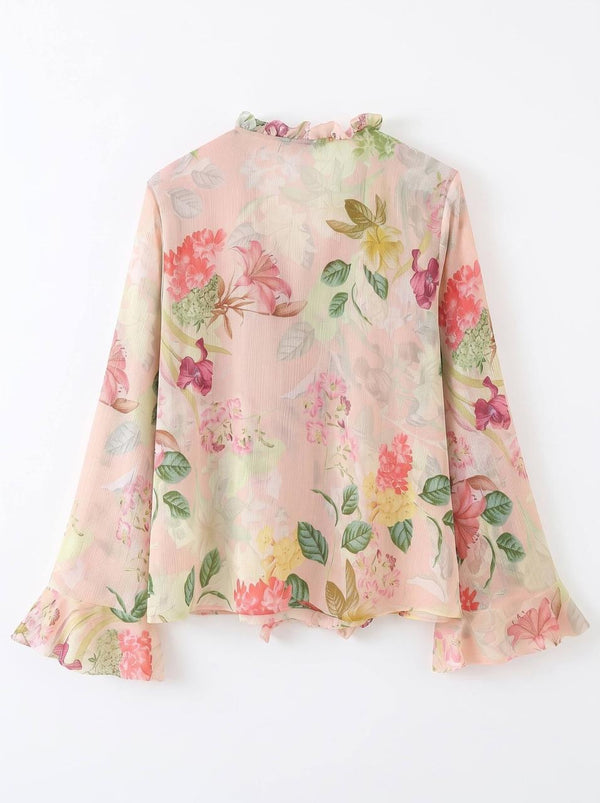 A long-sleeve blouse with a ruffled high neck and ruffled cuffs, featuring a soft pink base with a vibrant multicolor floral print in shades of red, yellow, and green.