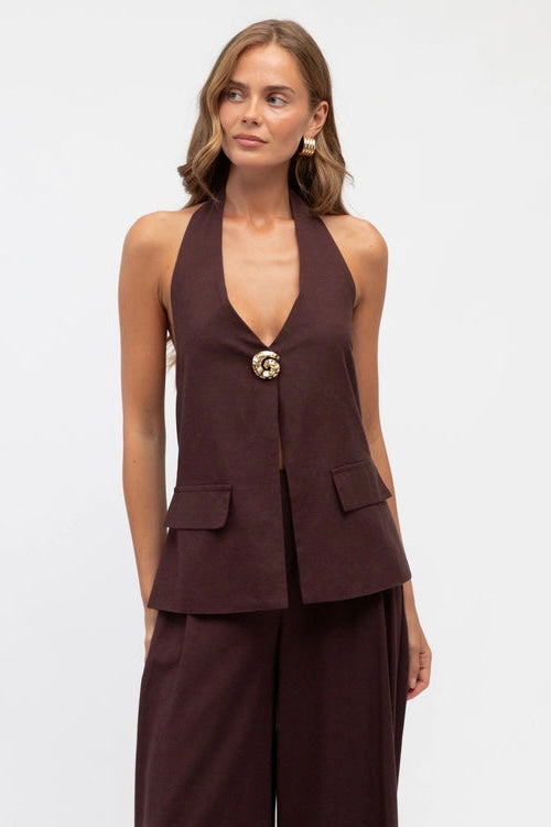 Woman wearing a brown halter top and wide-leg pants on a white background