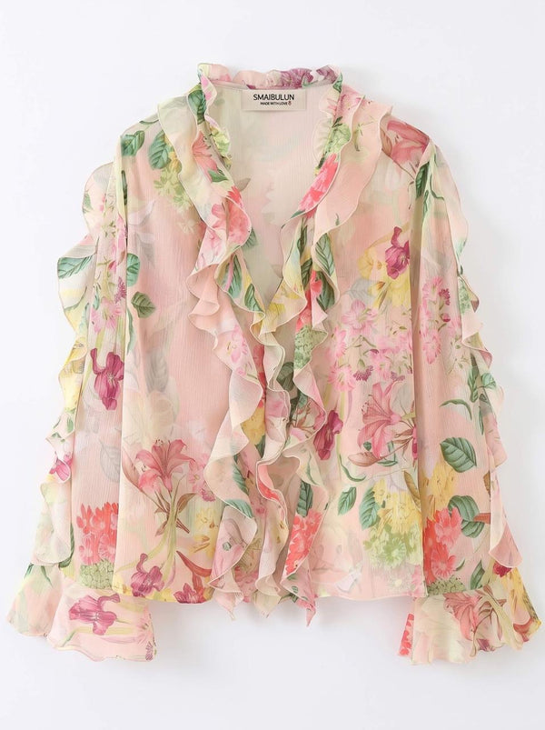 A lightweight, long-sleeve blouse with a soft pink base and a vibrant multicolor floral print, featuring layered ruffles along the front and collar. The brand name 'DANIELLA' is visible on the inner neck label.