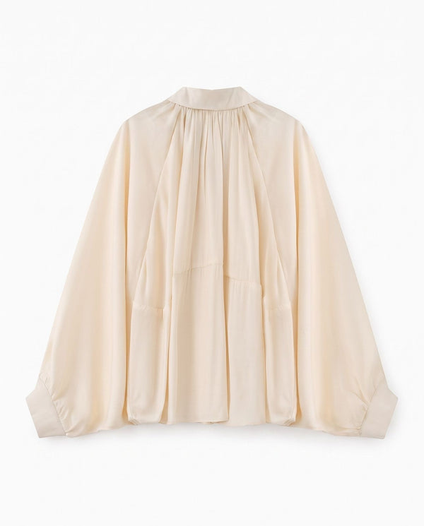 A light beige long-sleeve blouse with a high gathered neckline and pleated front details, shown flat against a white background.