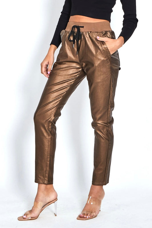Bronze metallic pants worn by a person on a white background