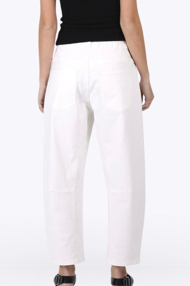 White cropped wide-leg pants with large patch pockets, shown on a model from the back wearing a black top and black sandals.
