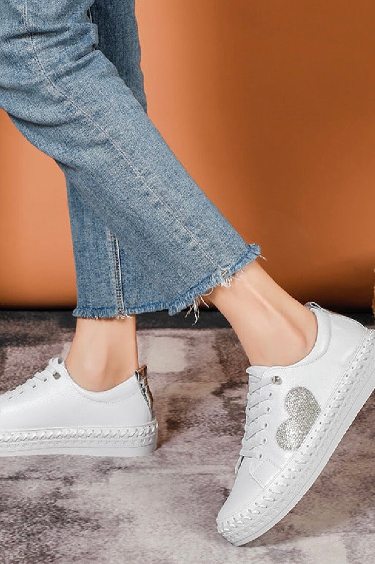White leather sneakers with a silver bling heart design worn with blue jeans