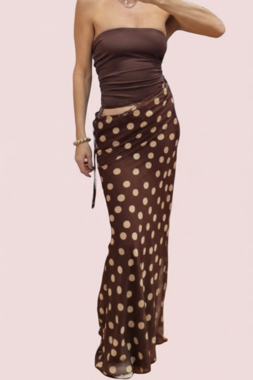 Woman taking a mirror selfie wearing a brown strapless top and polka dot skirt in a store.