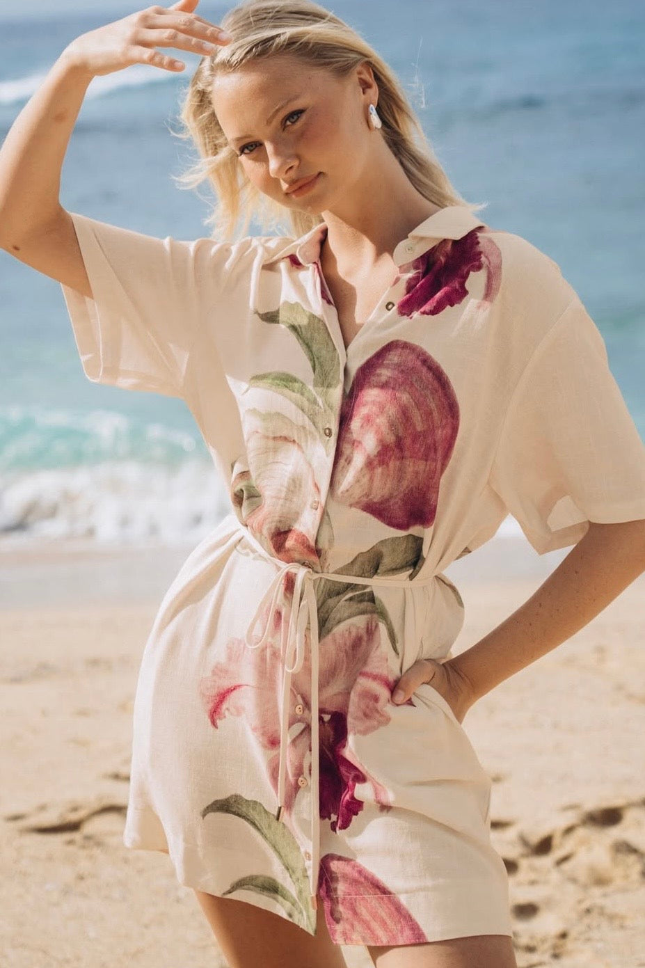 Woman wearing a floral shirt dress on a beach with ocean in the background
