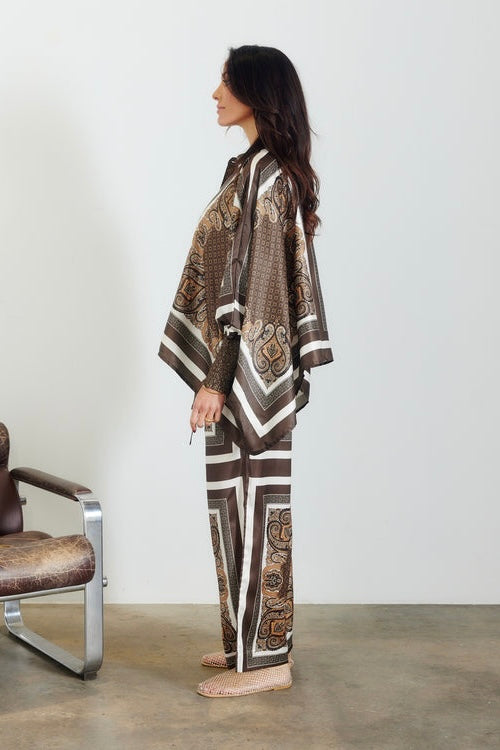 Taormina Scarf Pant — side profile full length view of relaxed wide-leg silhouette in chocolate paisley border print, styled with matching batwing top and woven sandals