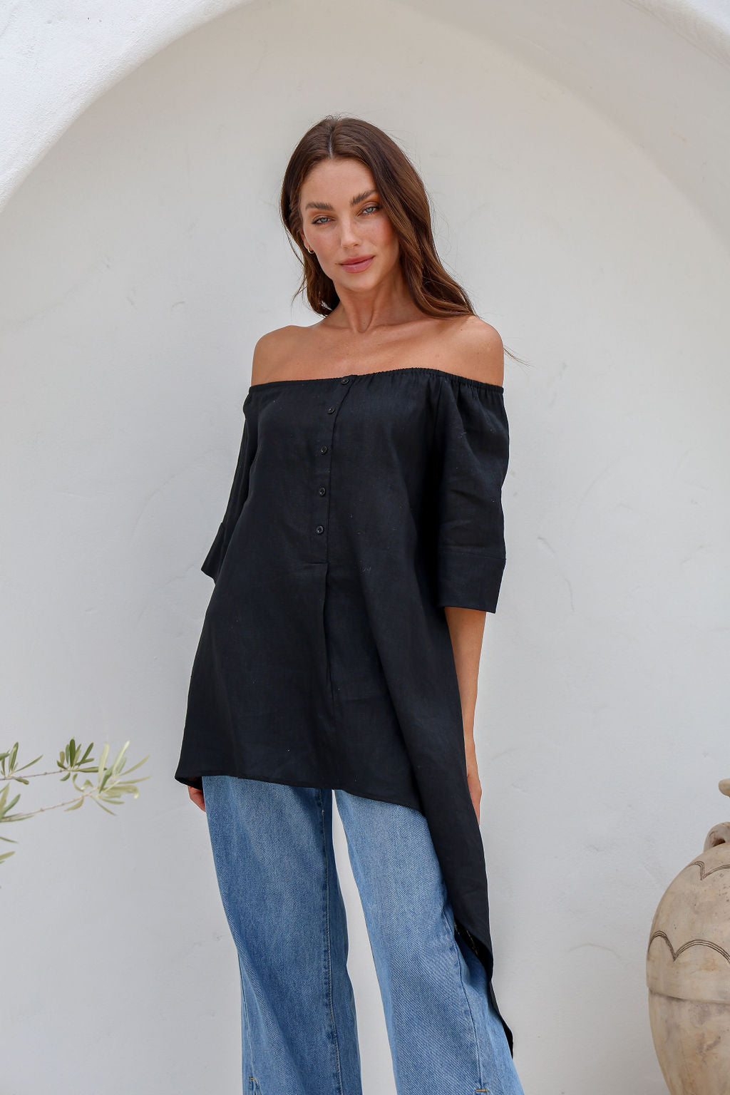 Woman wearing a black off-shoulder asymmetrical top and blue jeans 