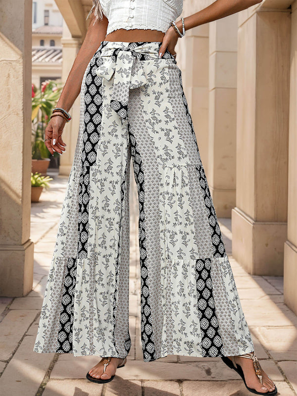 Person wearing a white top and patterned wide-leg pants standing in an outdoor setting.